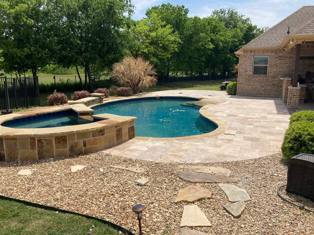 natural stone hardscape in backyard around hot tub and pool