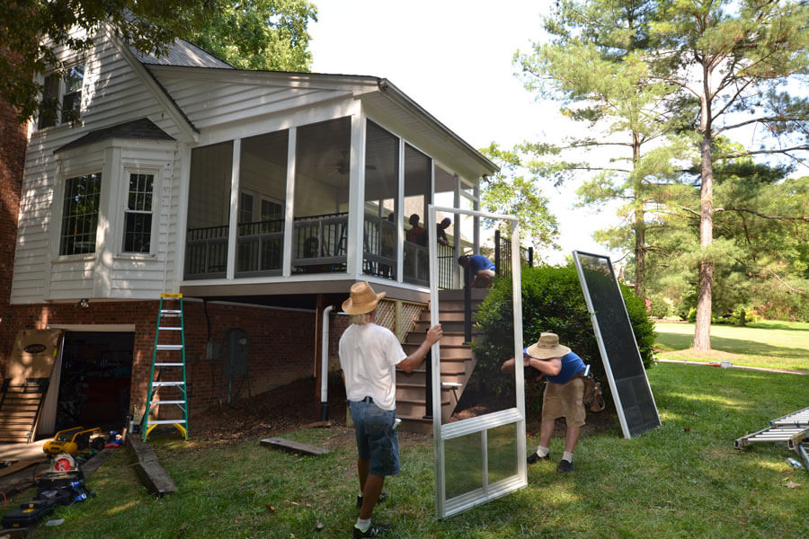 Family working on window to a screened porch