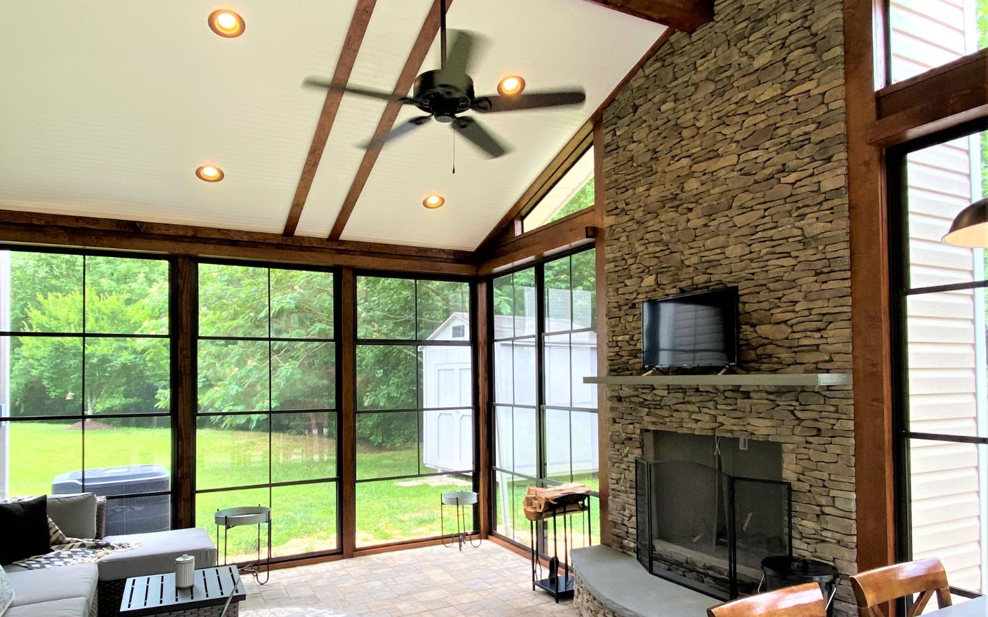 A room with a stone fireplace and a ceiling fan
AI-generated content may be incorrect.