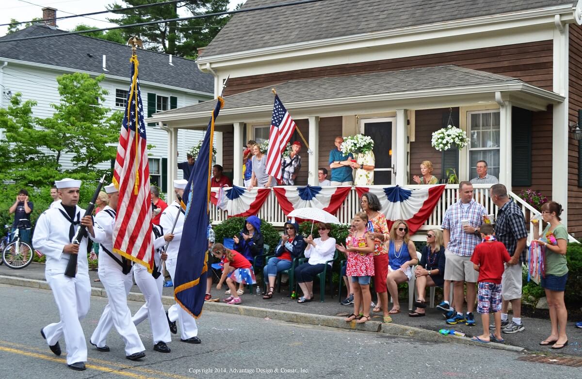 Family watching a fourth of July parade from their farmer's porch