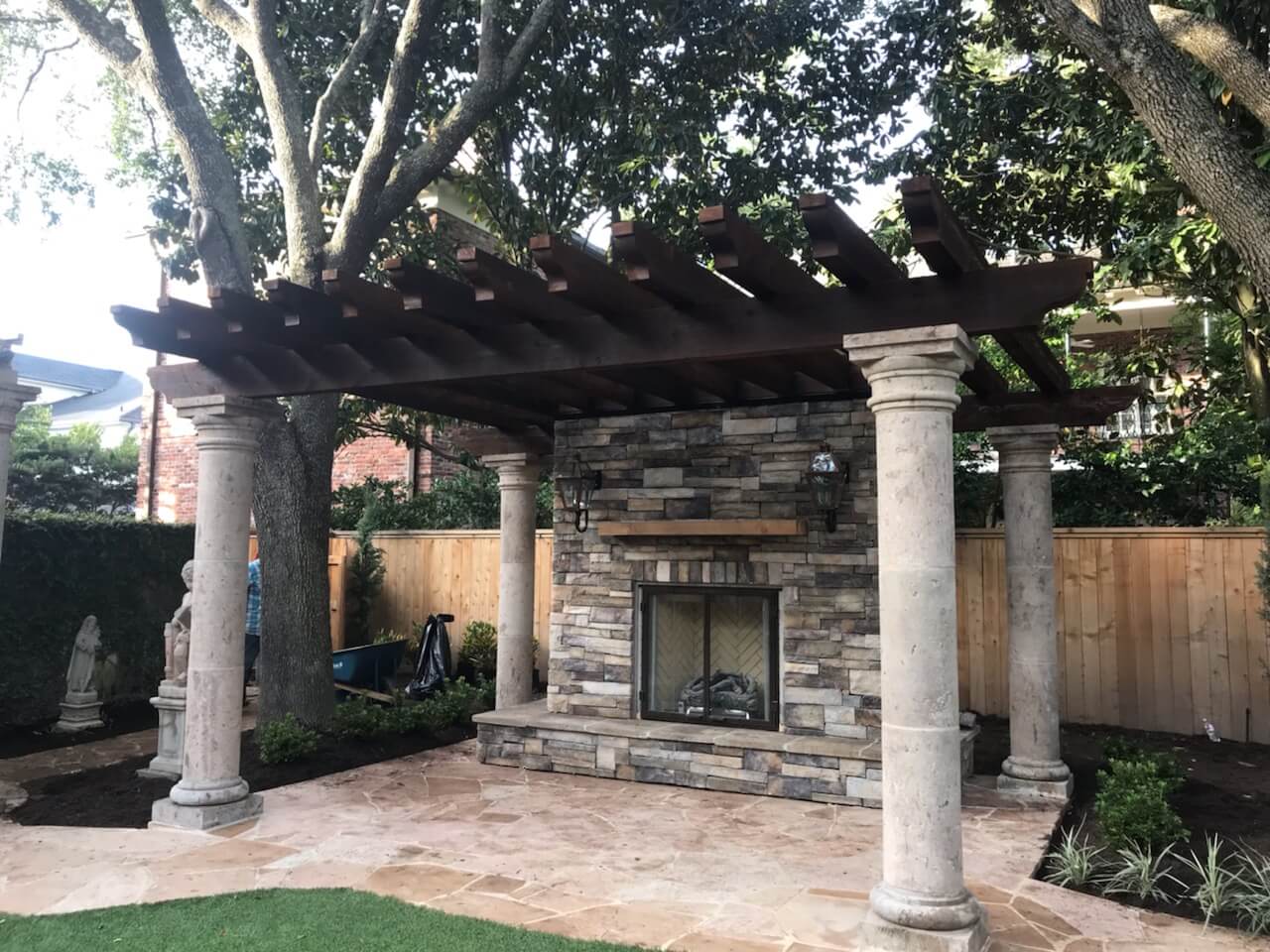 Custom Tuscan pergola design with stacked stone outdoor fireplace in Houston, TX