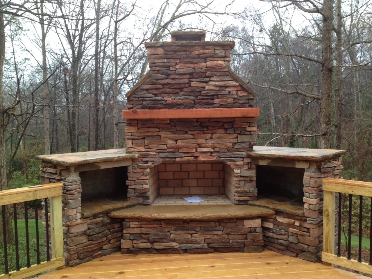 outdoor fireplace on wood deck with wood rail and deckorator metal pickets