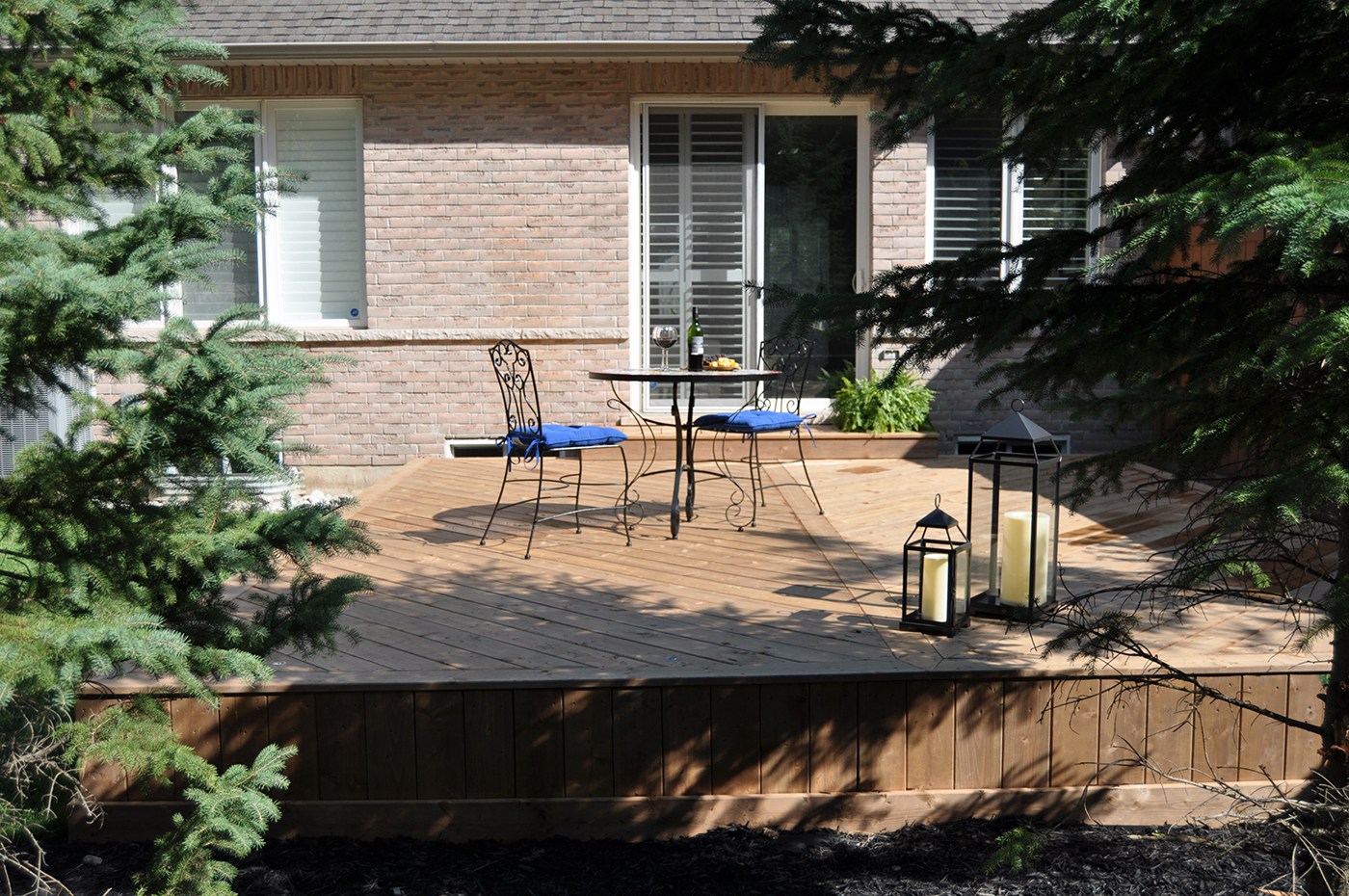 Backyard deck with table, chairs, and lanterns.