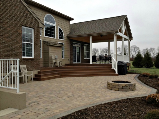 Back porch next to a patio with a built in firepit