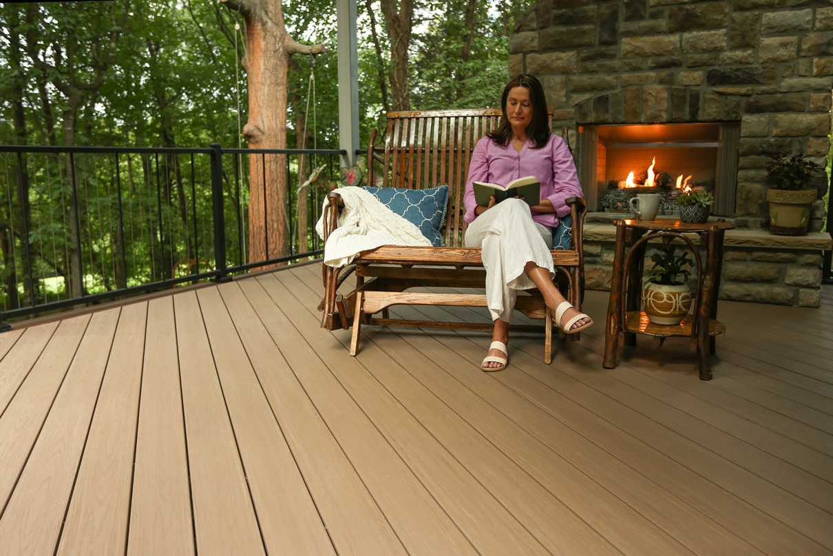 woman outside reading on her deck with fireplace